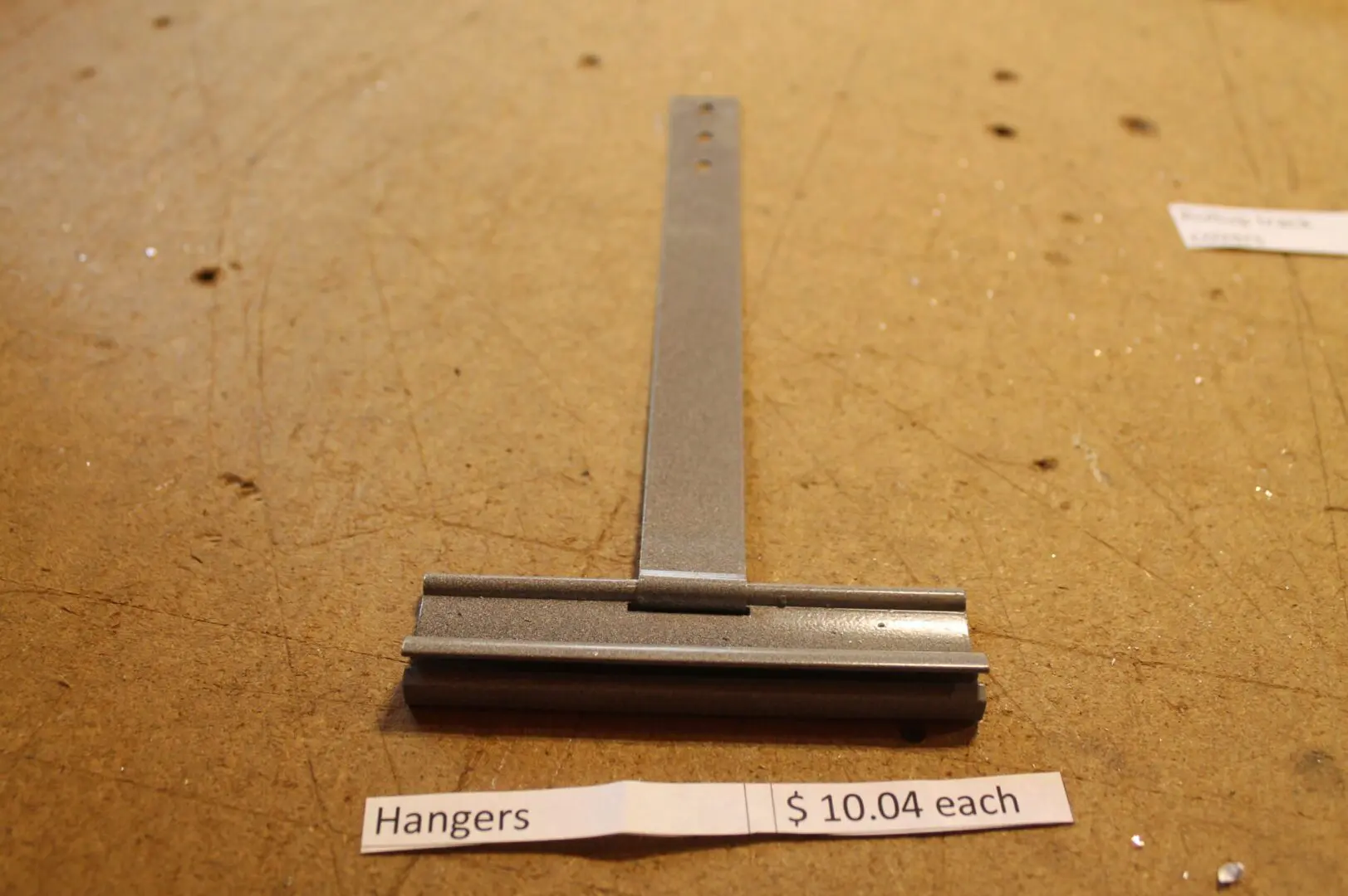 Metal hanger on wooden surface, $10.04.