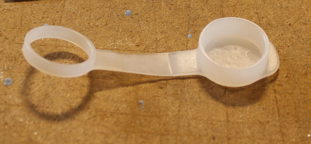 Plastic ring and cap on wooden surface.