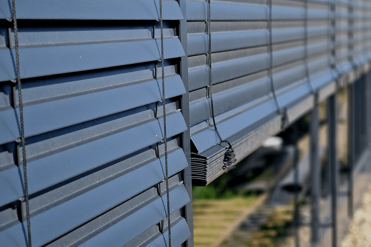Blue outdoor window blinds in sunlight.