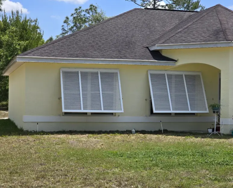 Yellow house with propped hurricane shutters